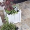 Biała donica drewniana Gardenity z plastikowym wkładem i ukrytymi kółkami, idealna do eleganckich wejść i tarasów